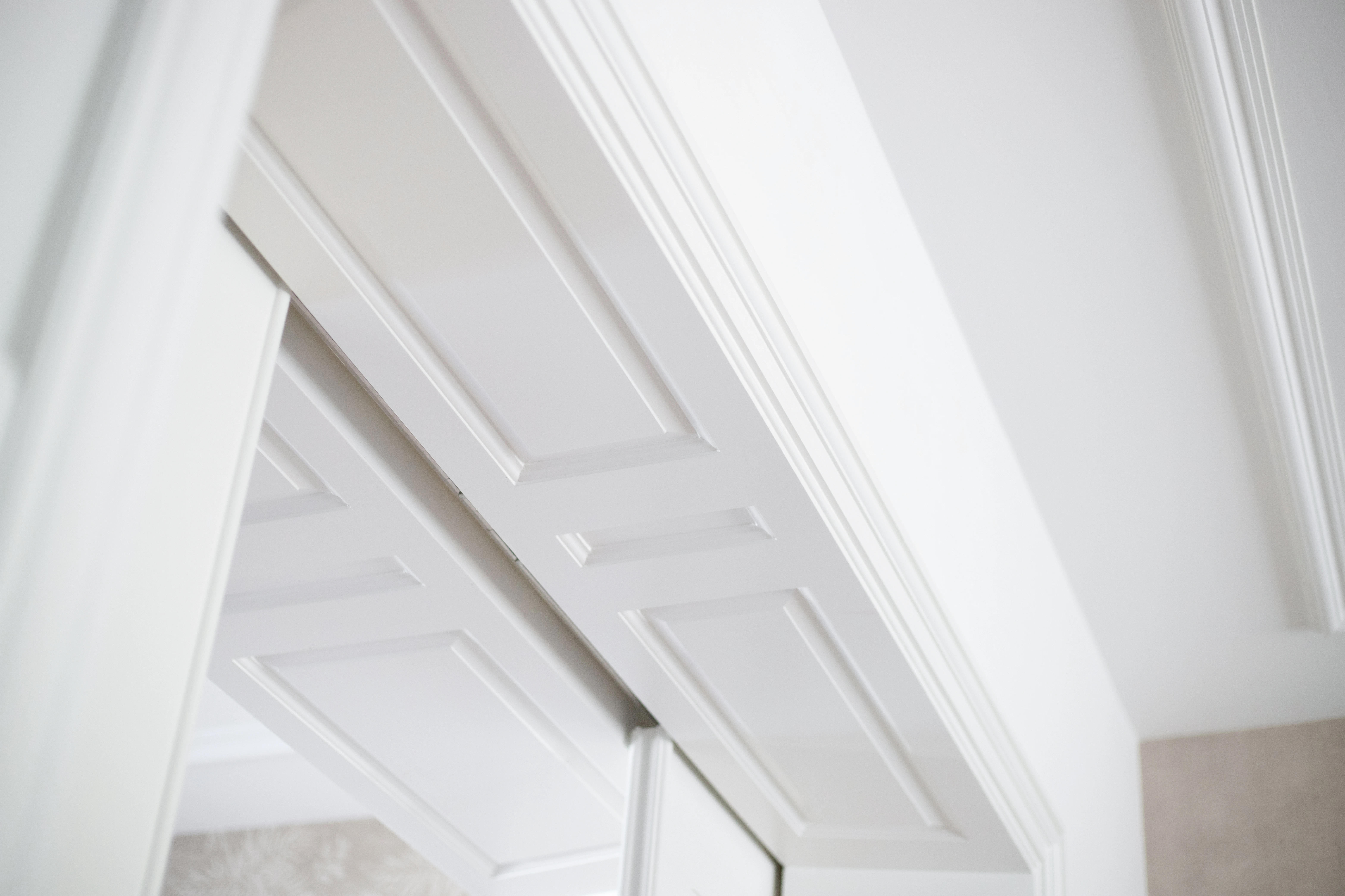 Detail van witte paneeldeuren en lijstwerk, gefotografeerd van onderaf