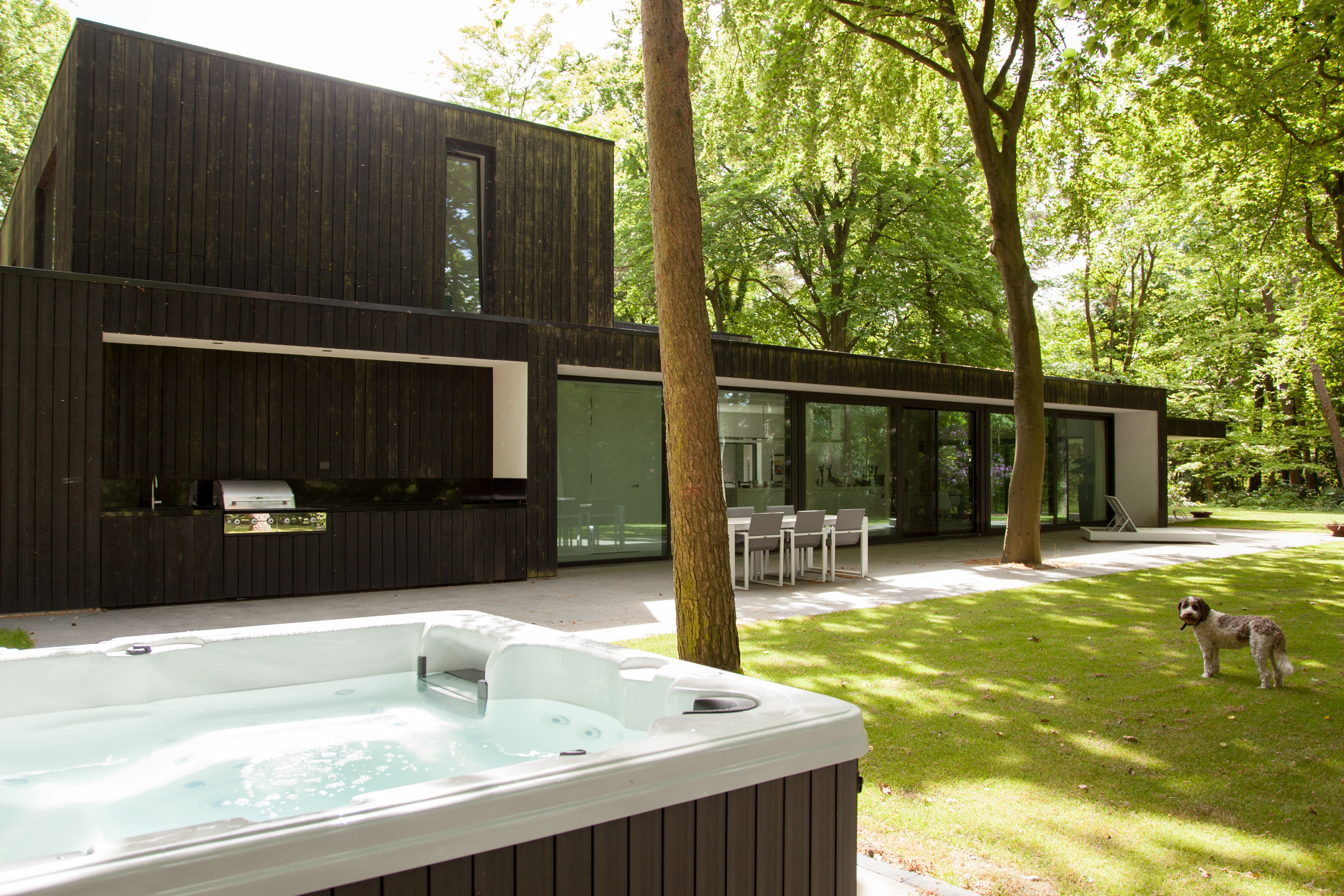 Achtergevel met buitenkeuken, terras en gazon, met een jacuzzi op de voorgrond