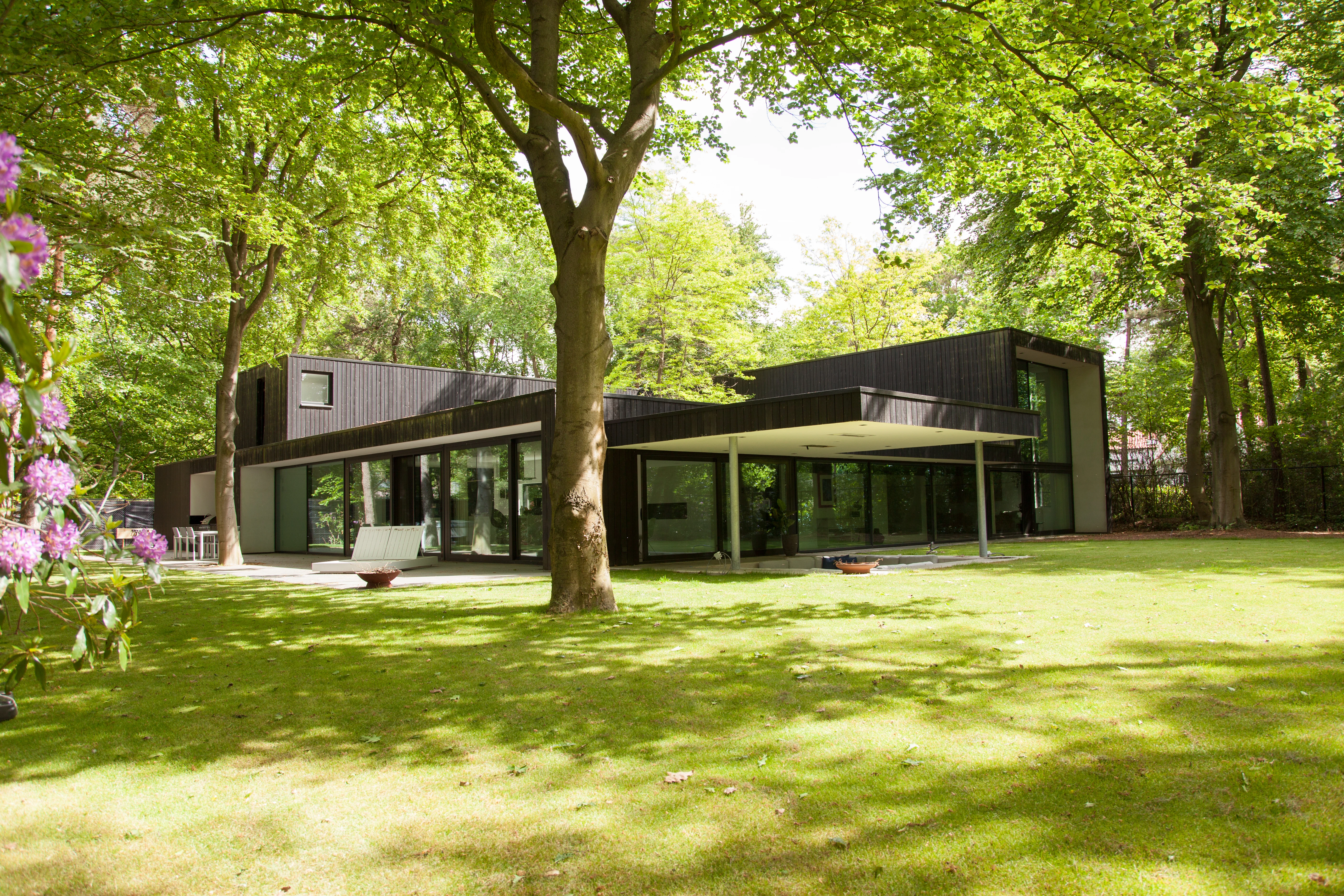 Villa tussen hoge bomen met een overdekt terras en een verlaagde zitkuil, vastgelegd als projectfoto