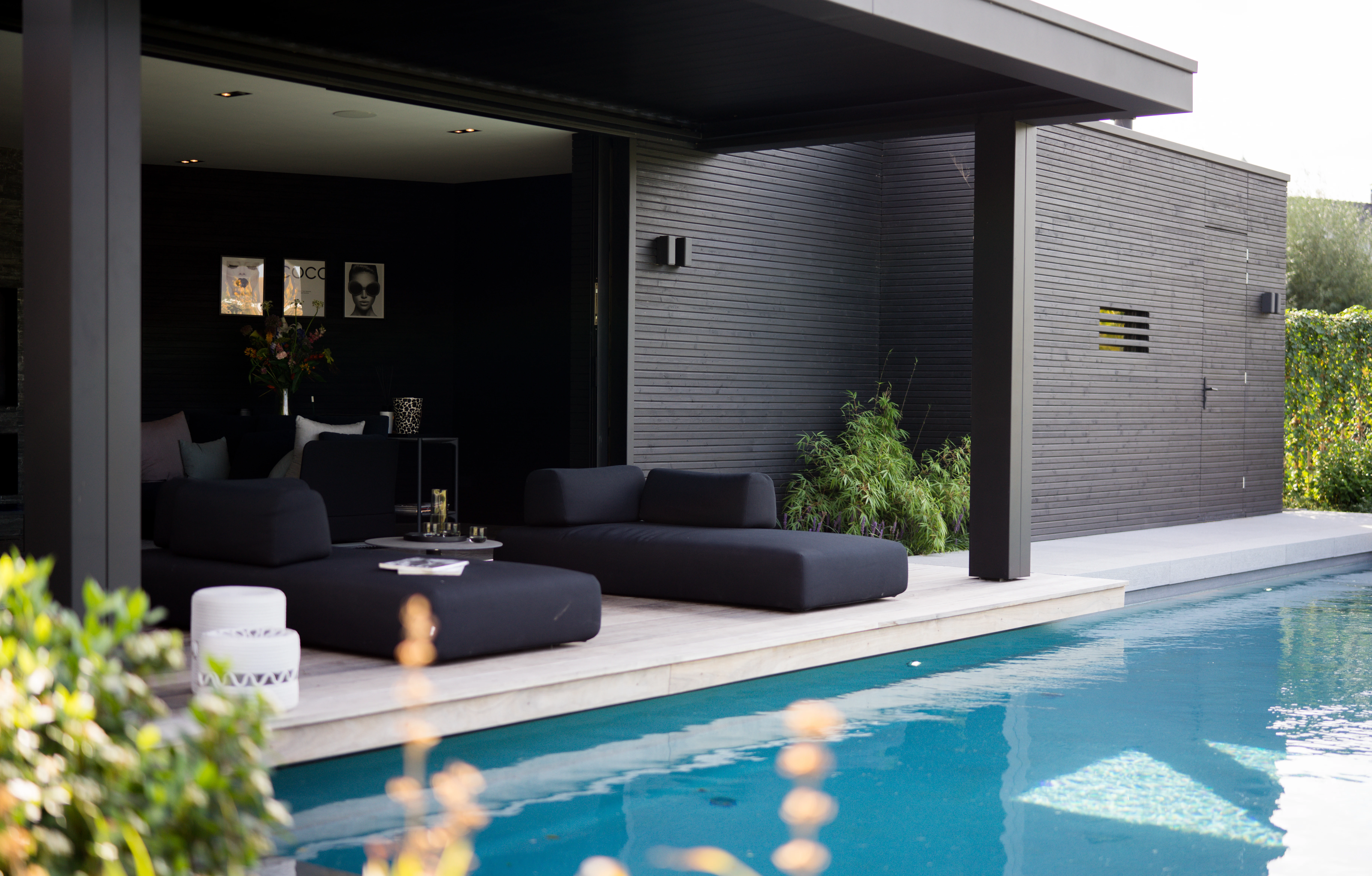 Loungehoek onder de overkapping van het poolhouse, naast het zwembad