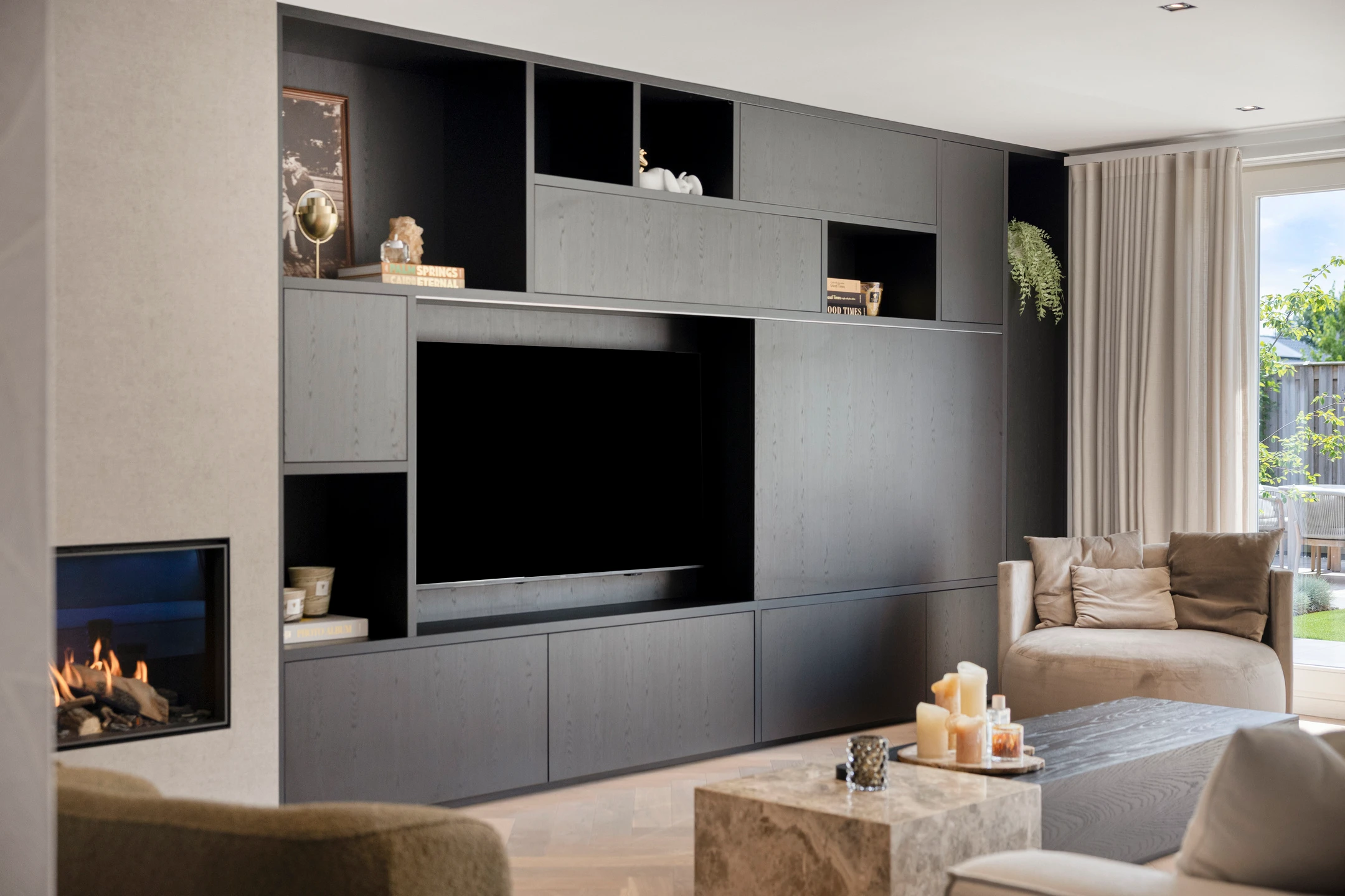 Woonkamer met een op maat gemaakte donkere tv-wand en open haard