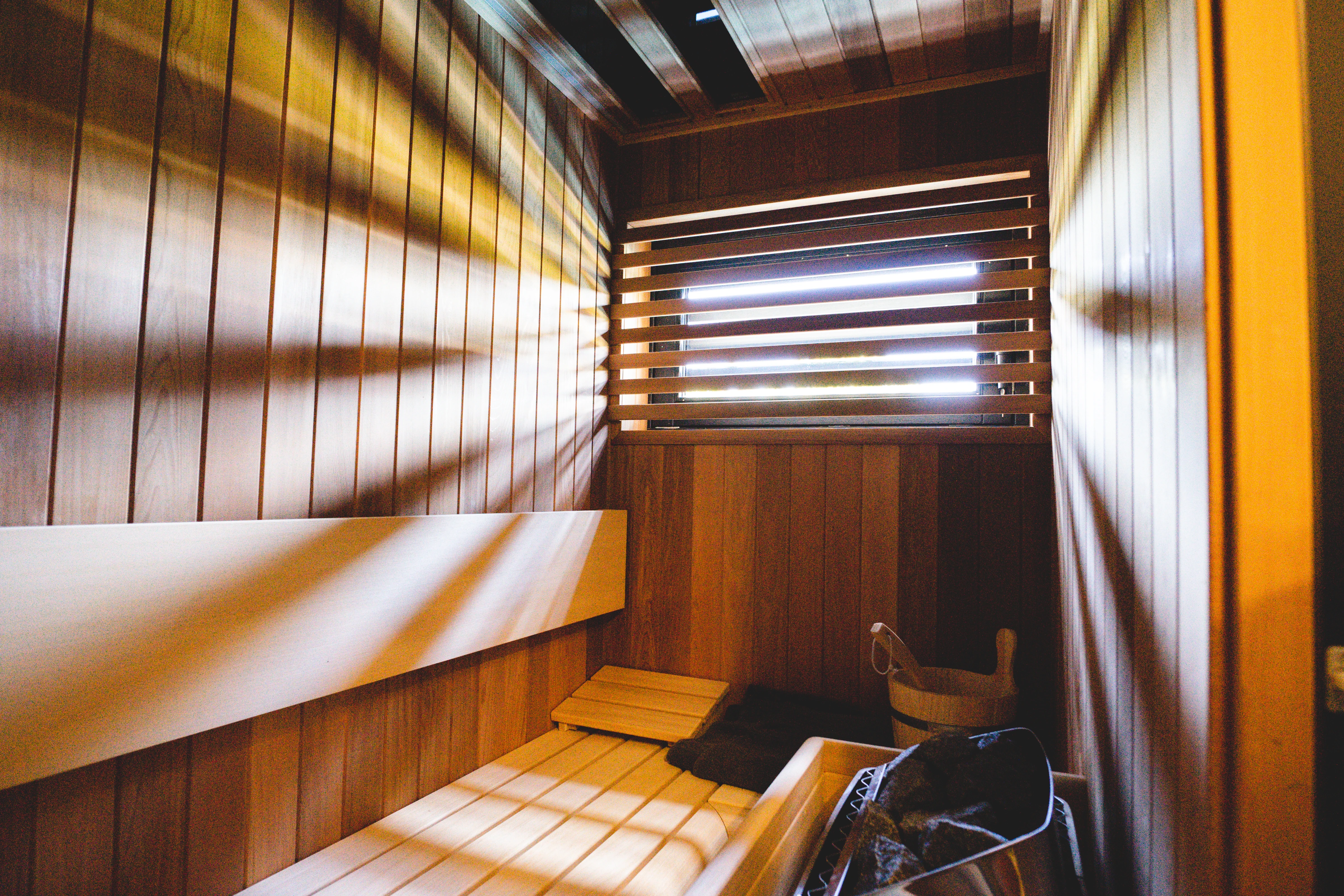 Sauna met houten interieur en lichtstrepen door de louvreblinden