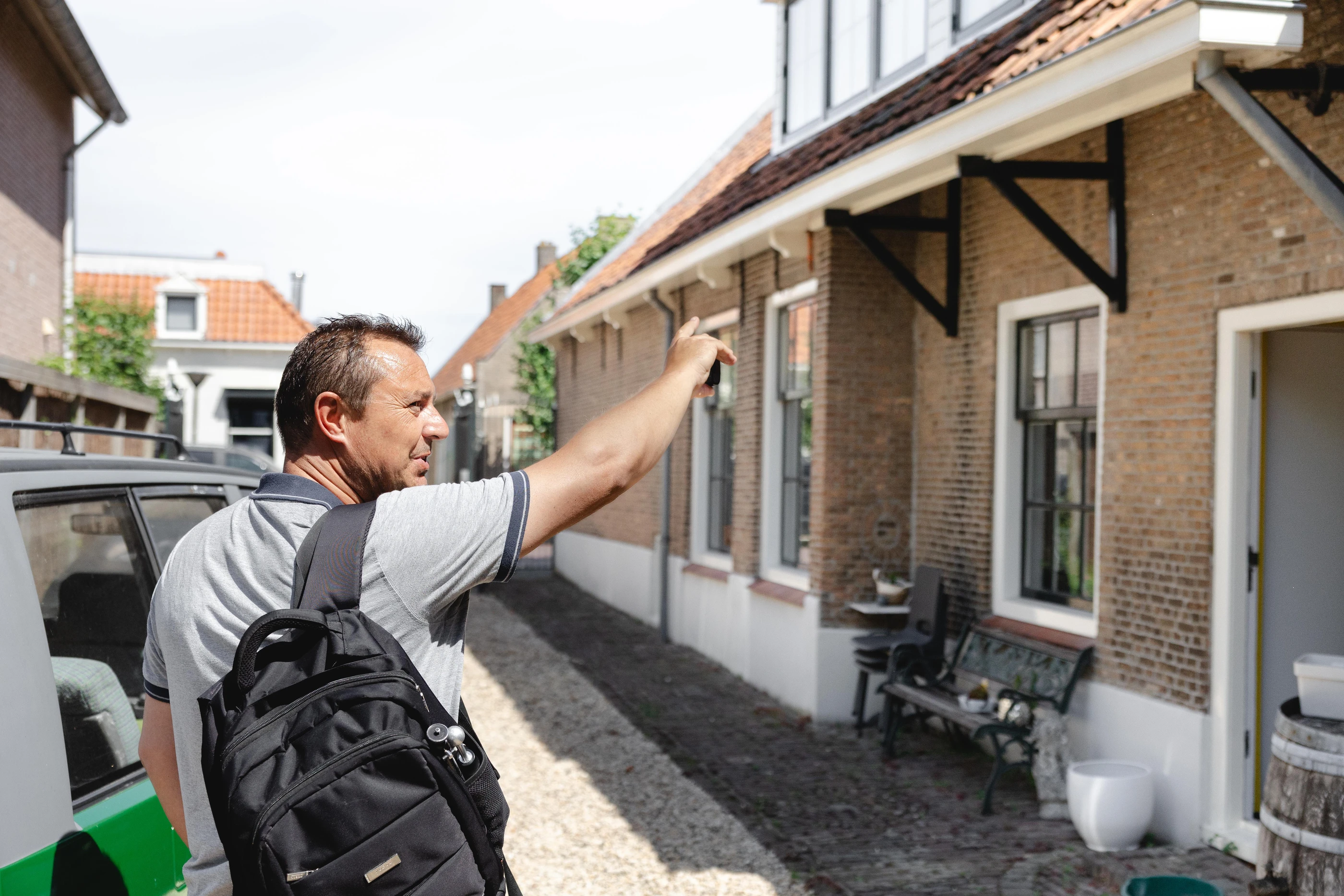 Inspecteur bekijkt de gevel van een oude woning in een smal straatje